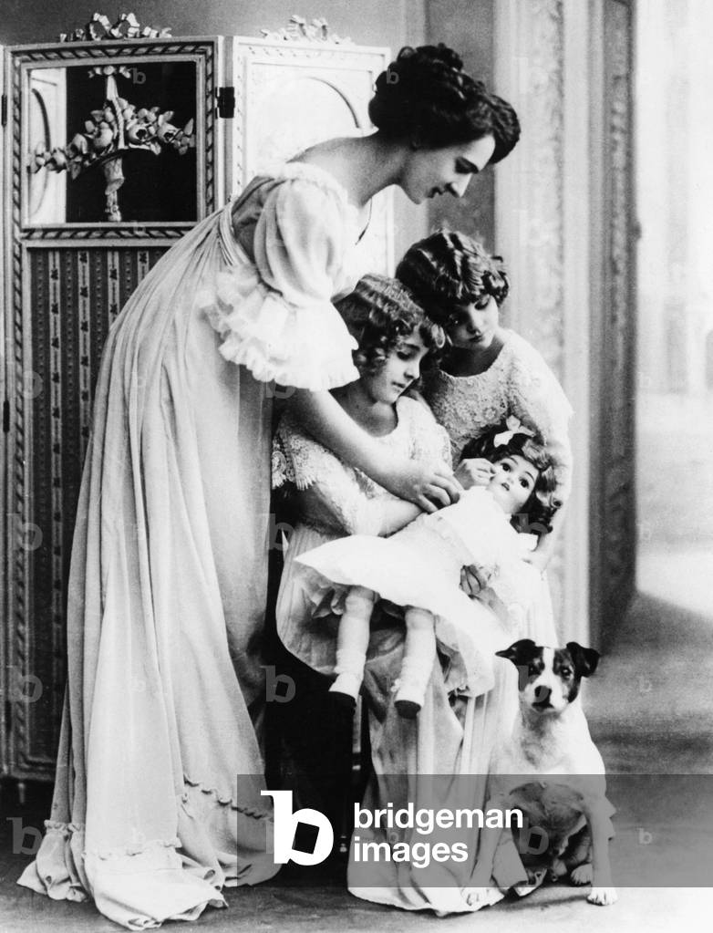 Mother instructs daughters in child care, 1910 (b/w photo)