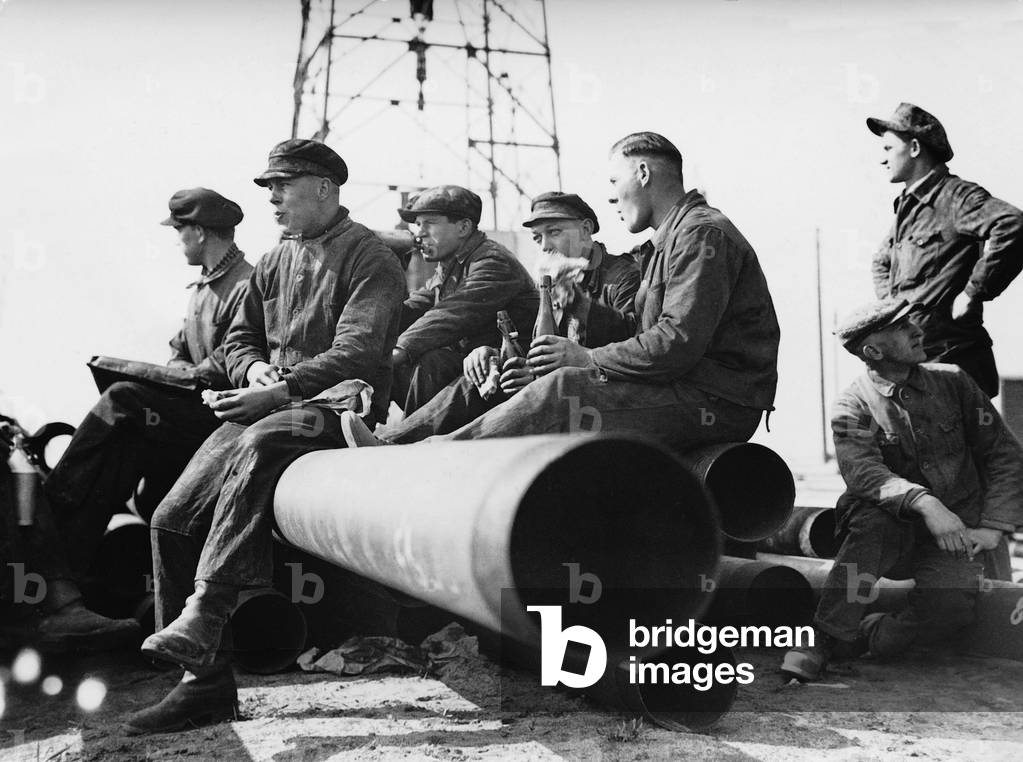Oil workers at the lunch break on casing pipes, 1934 (b/w photo)