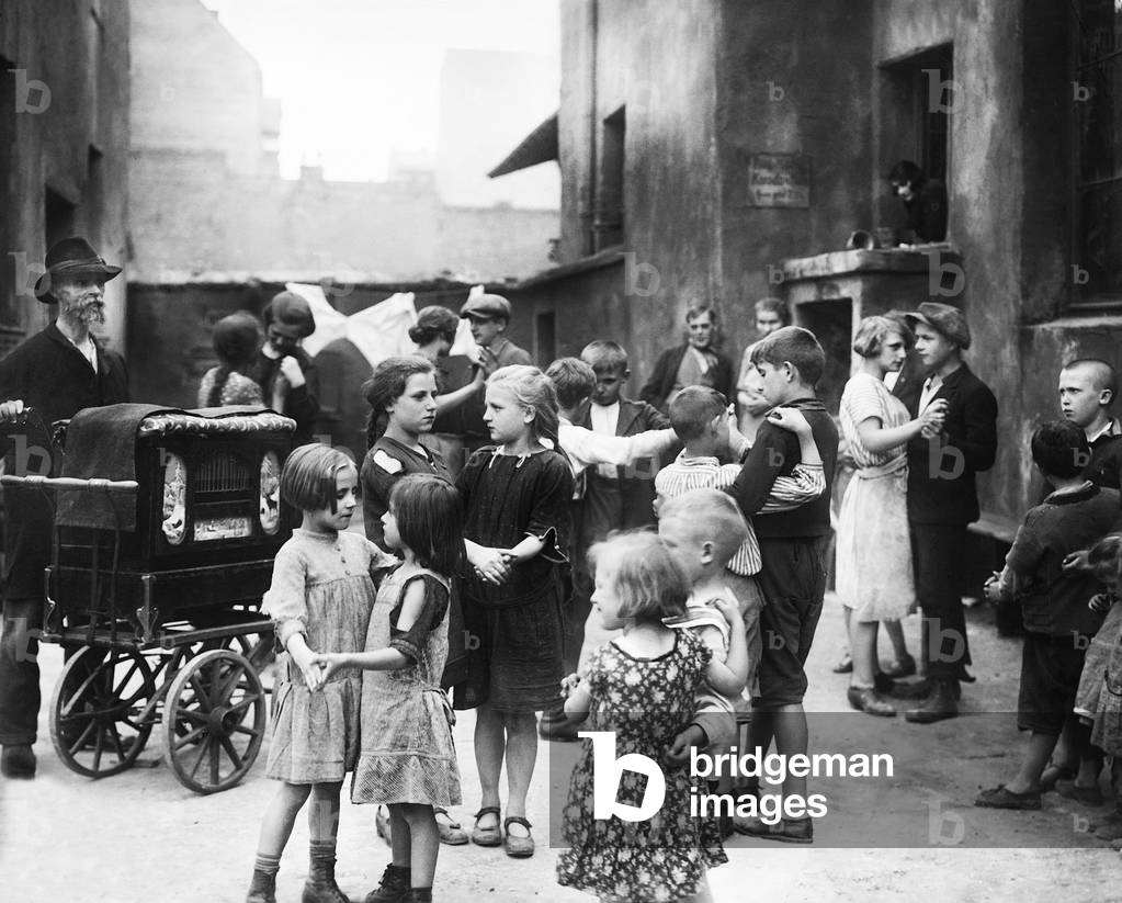 Children dance to barrel organ music, 1938 (b/w photo)