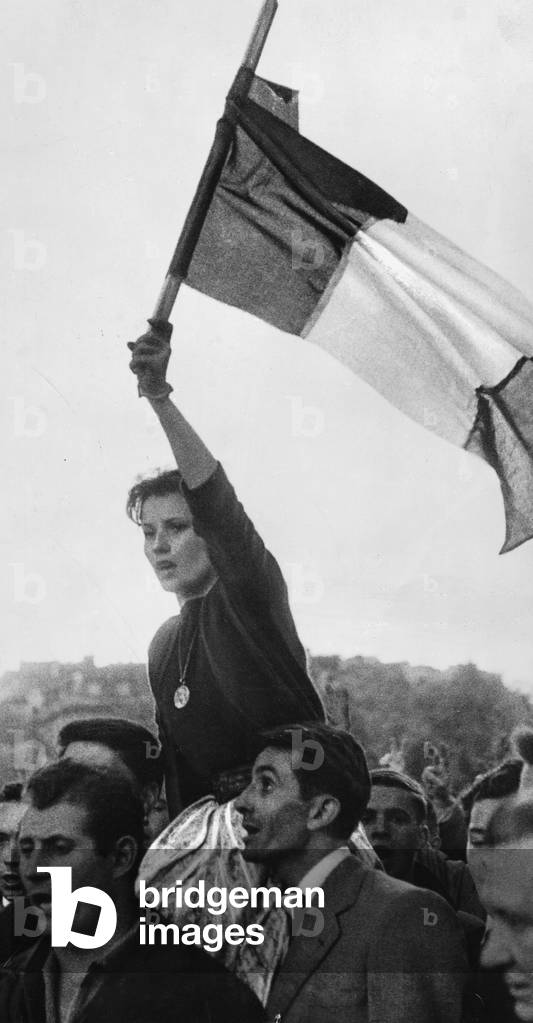 A woman waves the flag of France at a demonstration in Paris, 1958 (b/w photo)