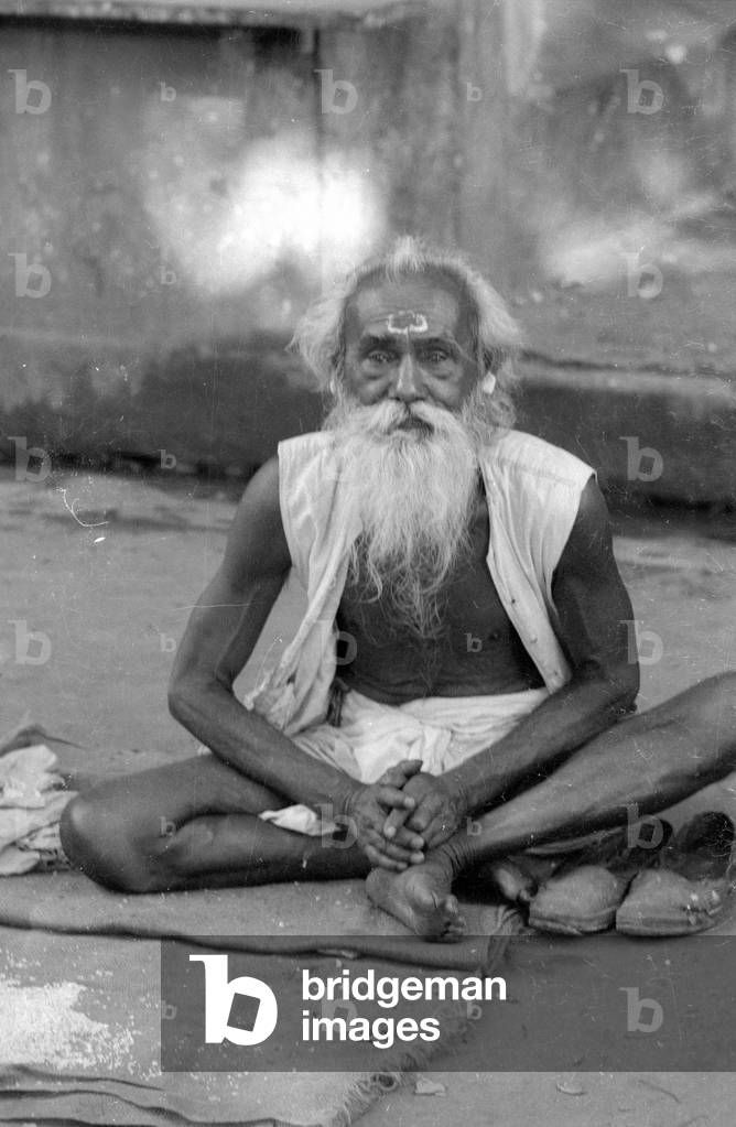 Indian sitting cross-legged in Benares, 1966 (b/w photo)