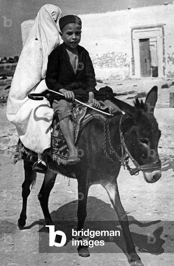 Young and veiled woman on a donkey, 1936 (b/w photo)