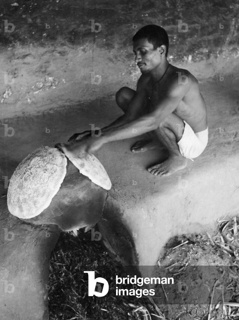 Indian mahout baking a flatbread (b/w photo)