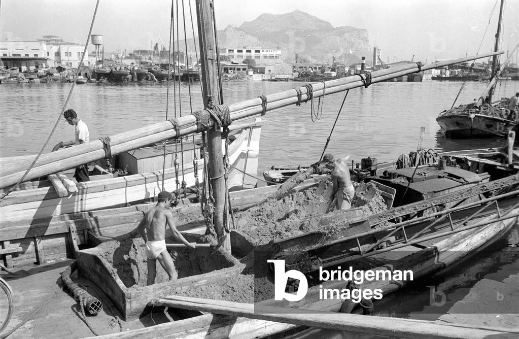 Dock workers in Palermo shoveling sand from a boat, 1963 (b/w photo)