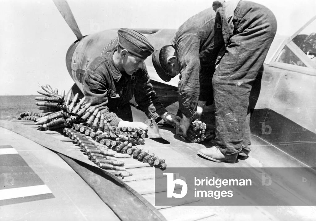 Ground crew reload ammunition in a fighter plane, 1942 (b/w photo)