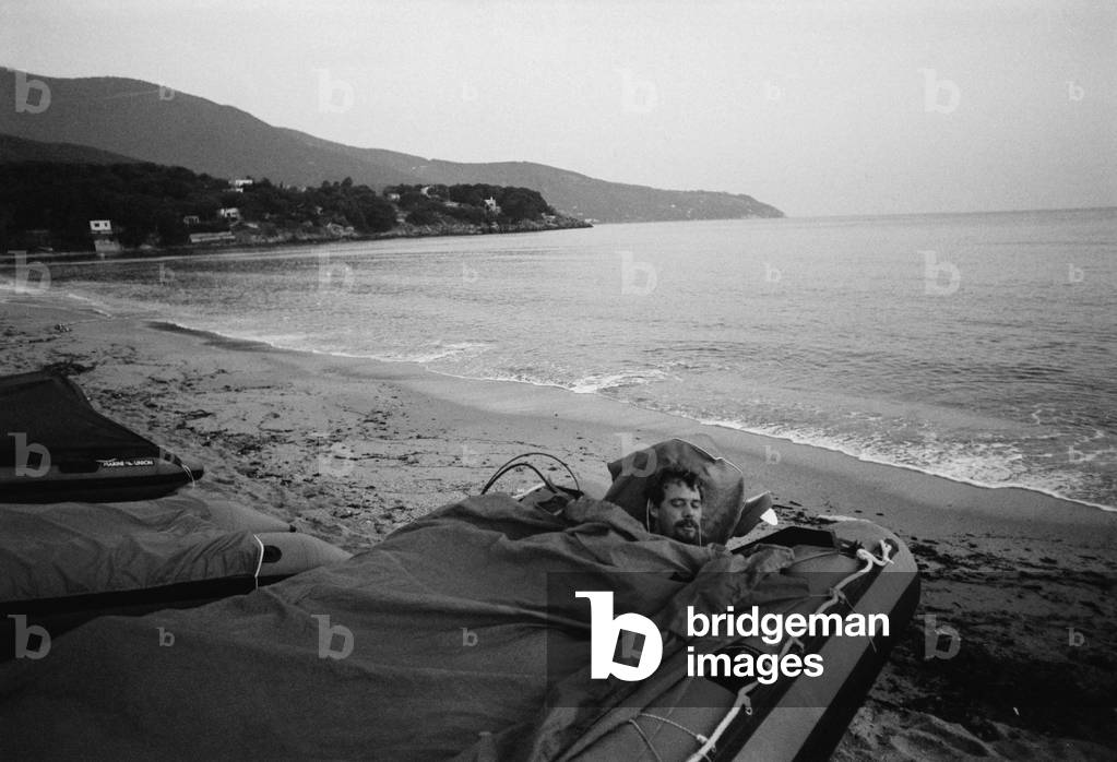 Man sleeps in his rubber dinghy in Italy (b/w photo)