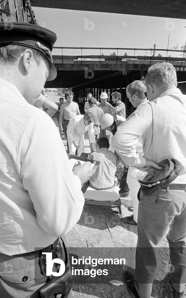 First aid following an accident at work on a construction site, 1970 (b/w photo)