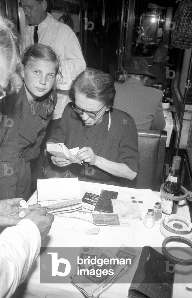 Rail traveller buys chocolate in the dining car, 1954 (b/w photo)