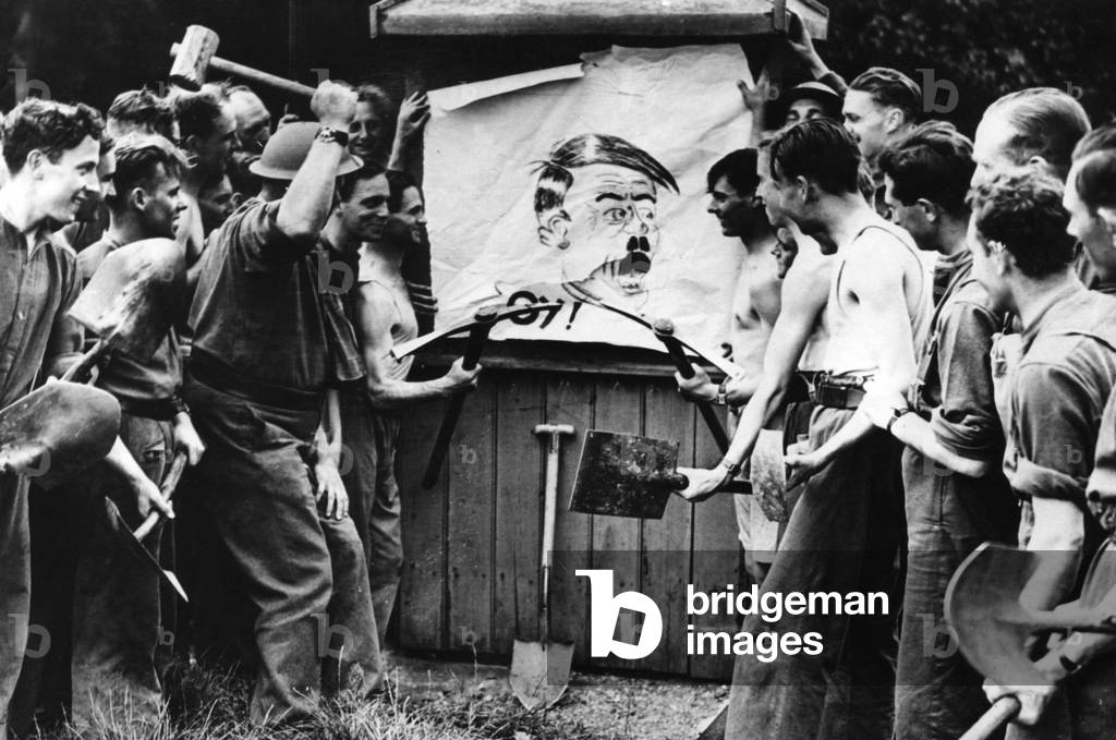 Men destroy a Hitler illustration, 1939 (b/w photo)