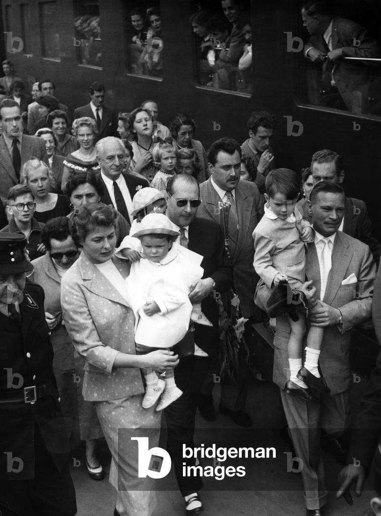 Roberto Rosselini (with sunglasses) and Ingrid Bergman make their way through the crowd at Munich's main station, which has arrived to greet Bergman, August 1954 (b/w photo)