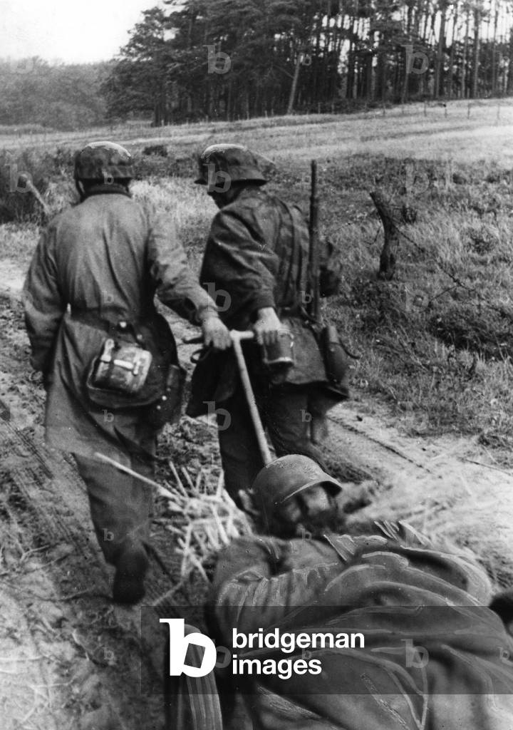 Wounded soldier in a hand carriage in the battle area Bergen op Zoom, 1944 (b/w photo)