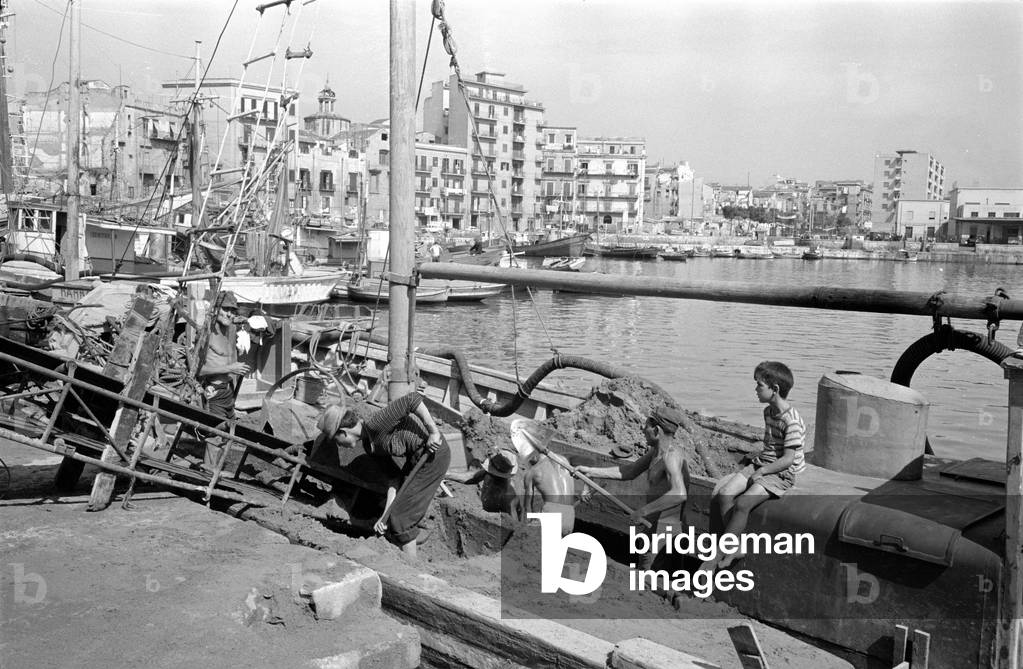Dock workers in Palermo shoveling sand from a boat, 1963 (b/w photo)