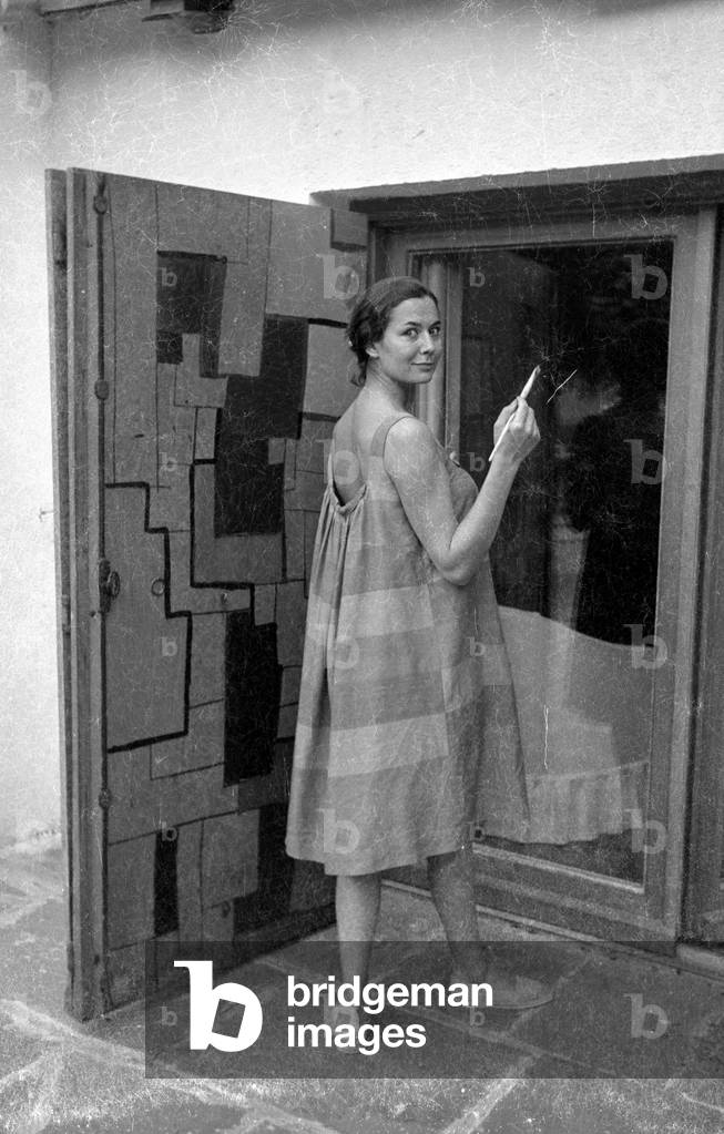 Simone Bicheron painting a wooden door, 1959 (b/w photo)