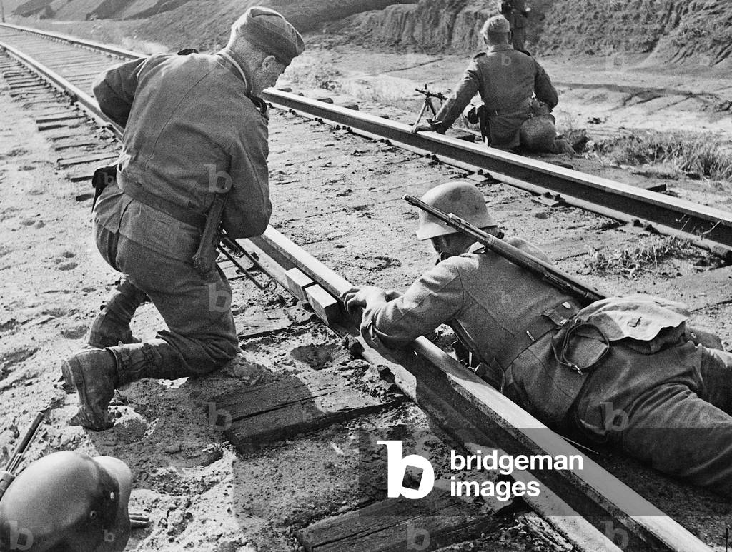 German engineers remove an explosive charge from railway tracks (b/w photo)
