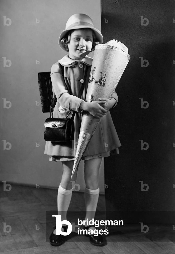 Girl with big cone of candy, a custom on the first day of school, 1935 (b/w photo)
