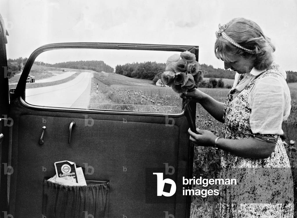 A woman with a bouquet of flowers on the motorway, 1939 (b/w photo)