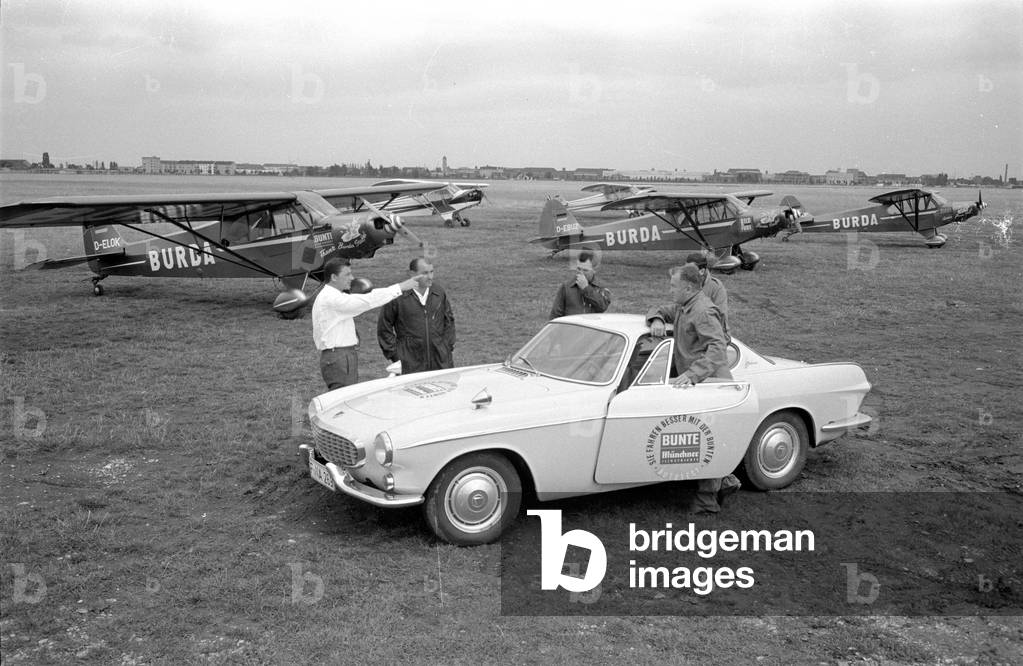 A Volvo P1800 S in front of the planes of the Burda squadron, 1963 (b/w photo)