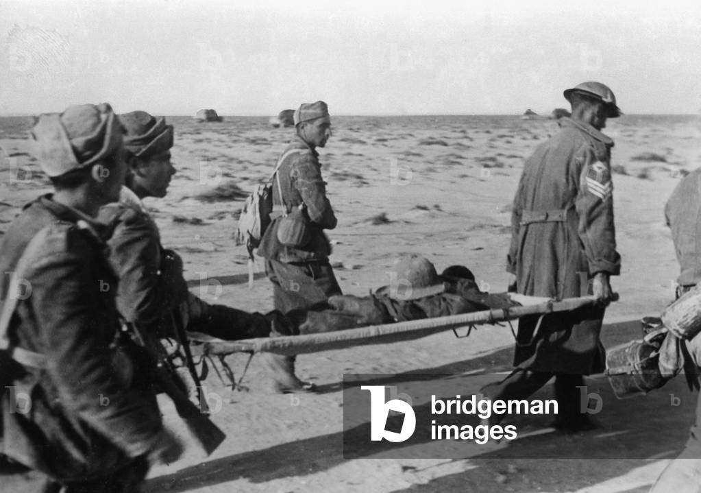 Italian troops carrying a wounded British prisoner during the First German offensive on Tobruk, Libya, 1941 (b/w photo)