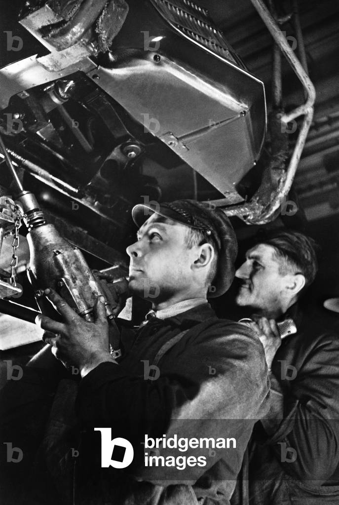 Industrial workers assembling an engine (b/w photo)