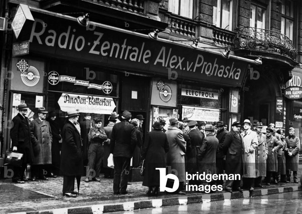 People listen to a Hitler speech before a radio shop, 1940 (b/w photo)
