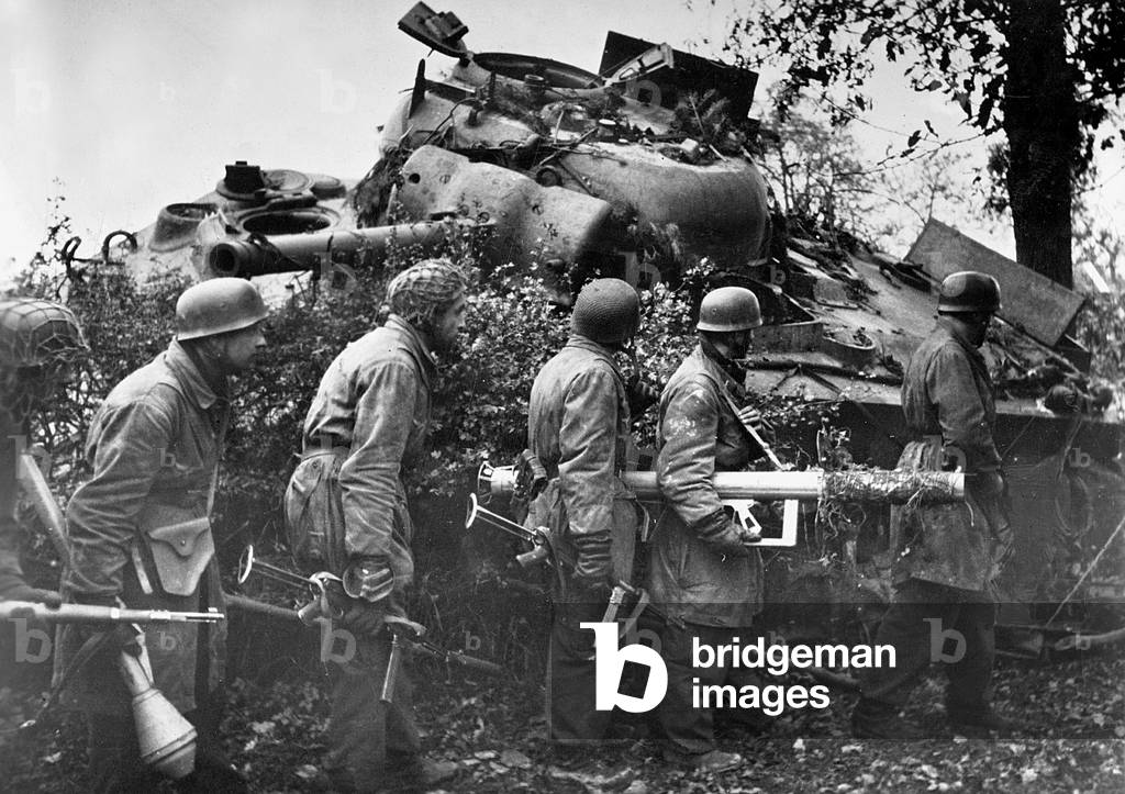 German soldiers gathered behind the wreckage of an American M4 Sherman tank, carrying anti-tank weapons, Holland, 1944 (b/w photo)