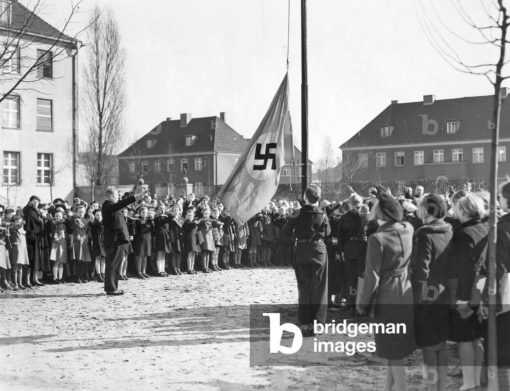 Students and teachers take down the swastika flag, 1939 (b/w photo)