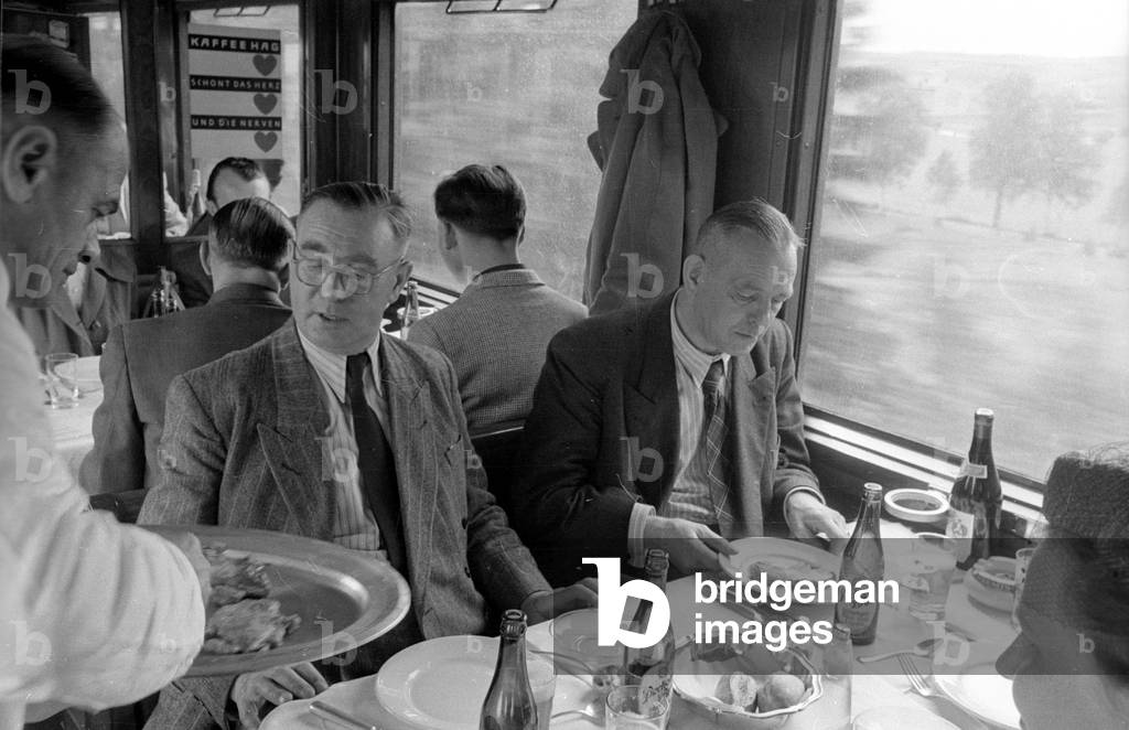 Waiter serving food to travelers, 1954 (b/w photo)