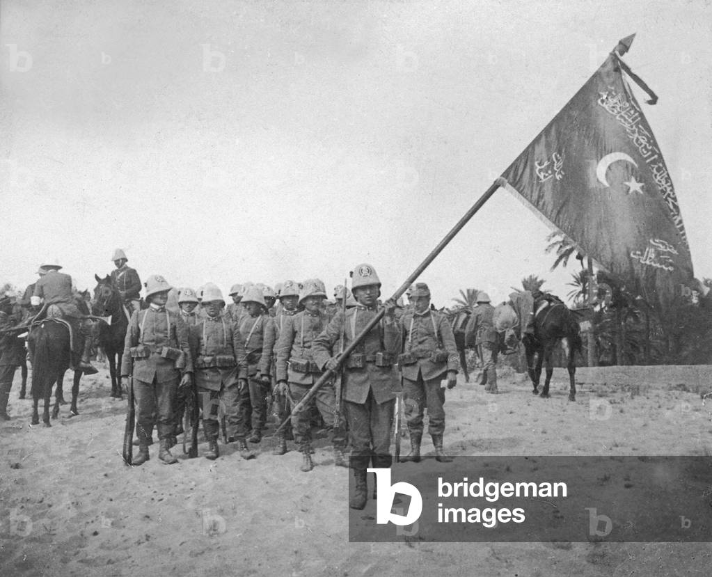 Italian troops in Libya with a captured flag of the Ottoman troops, 1911 (b/w photo)