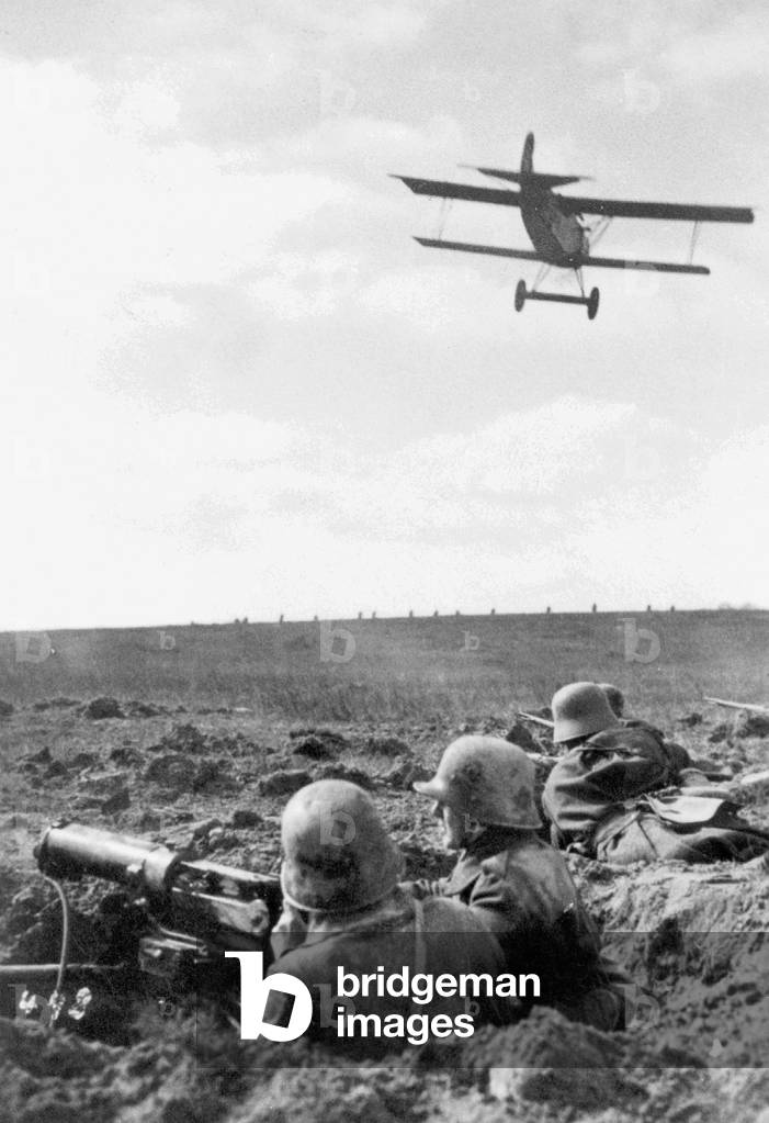 Fighter plane skims over German soldiers on the Western front, 1918 (b/w photo)
