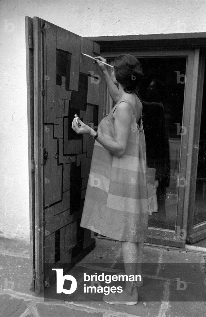 Simone Bicheron painting a wooden door, 1959 (b/w photo)
