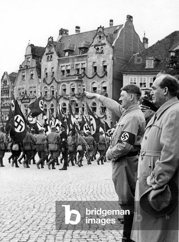 Gyula Goemboes with Adolf Hitler inspect an SA procession, 1933 (b/w photo)