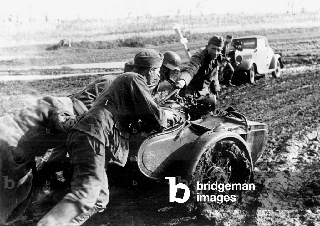German soldiers push a motorcycle with a sidecar which stranded in the mud, 1941 (b/w photo)