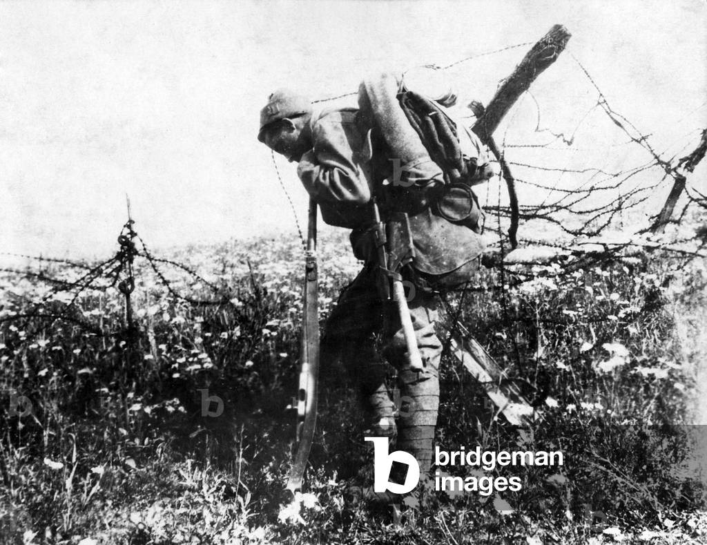 A French soldier leans on his rifle on a battle field at Verdun, 1916 (b/w photo)