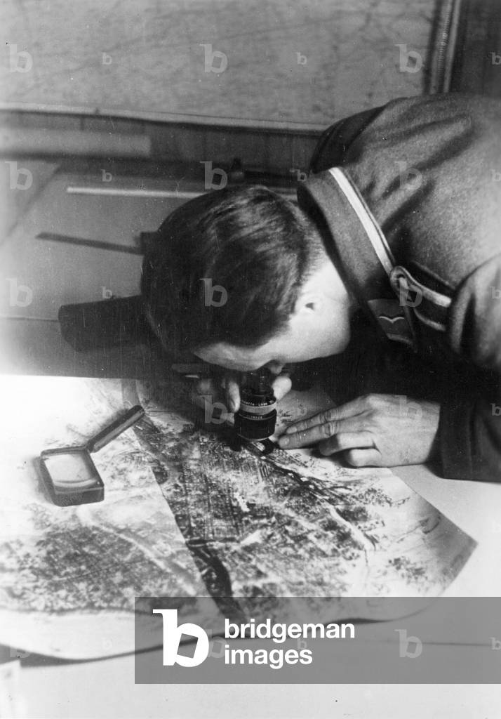 German soldier analyses reconnaissance images, 1941 (b/w photo)