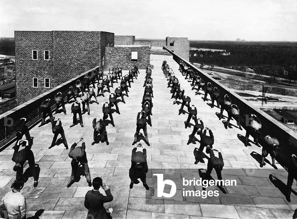 Employees are doing gymnastics on the rooftop of Siemens-Schuckertwerke in Berlin, 1931 (b/w photo)