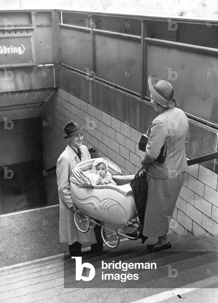 A man and a woman carry a pram, 1942 (b/w photo)