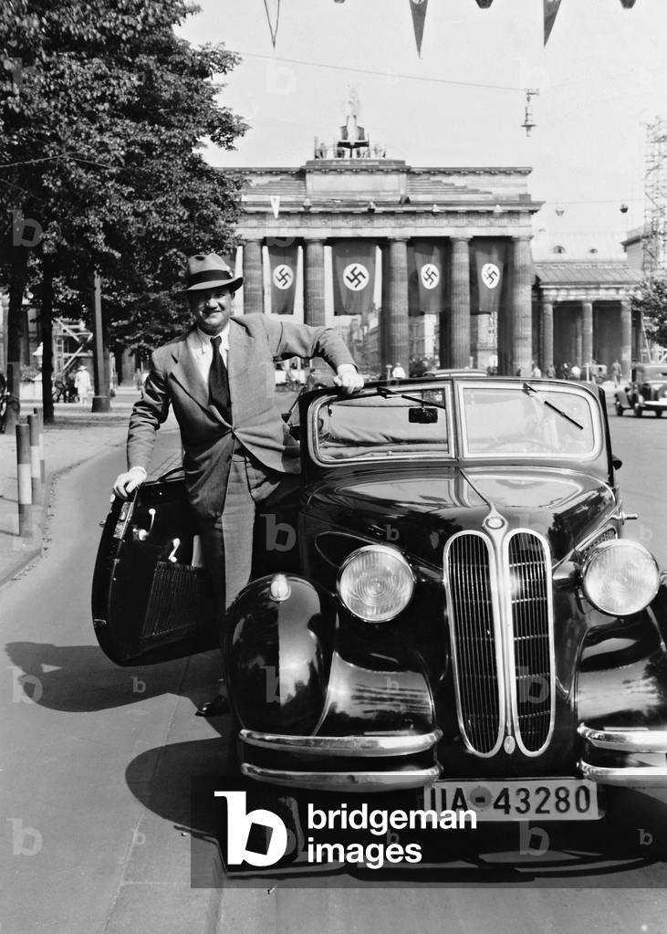 Fritz Kampers with his BMW car in front of the Brandenburg Gate (b/w photo)