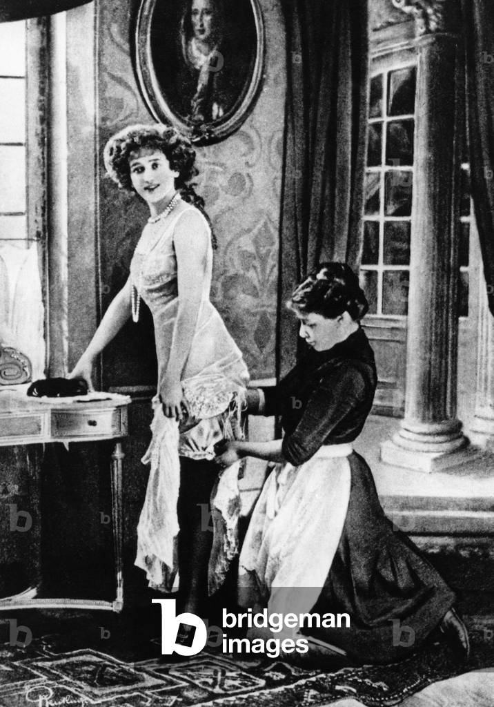 A maid helping her mistress dress, early 1920s (b/w photo)