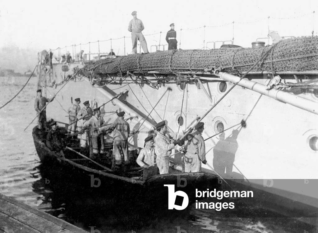 Crew clean the exterior walls of a war ship, 1916 (b/w photo)