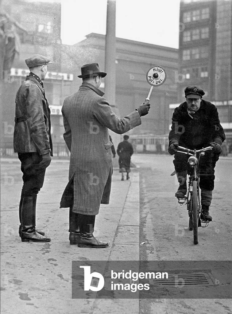 Plain clothes police officers stop a cyclist, 1942 (b/w photo)