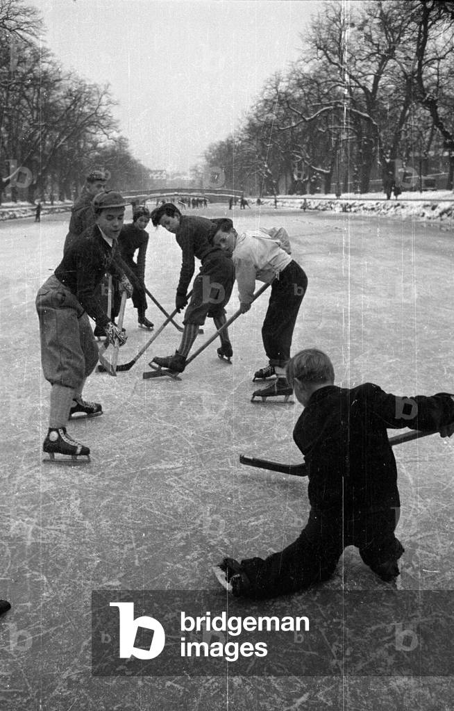 Children playing ice hockey on the frozen Nymphenburg Canal, 1957 (b/w photo)