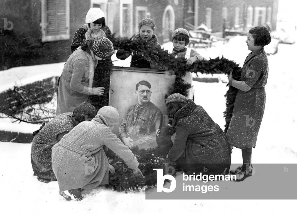 Children decorate a picture of Hitler, 1935 (b/w photo)