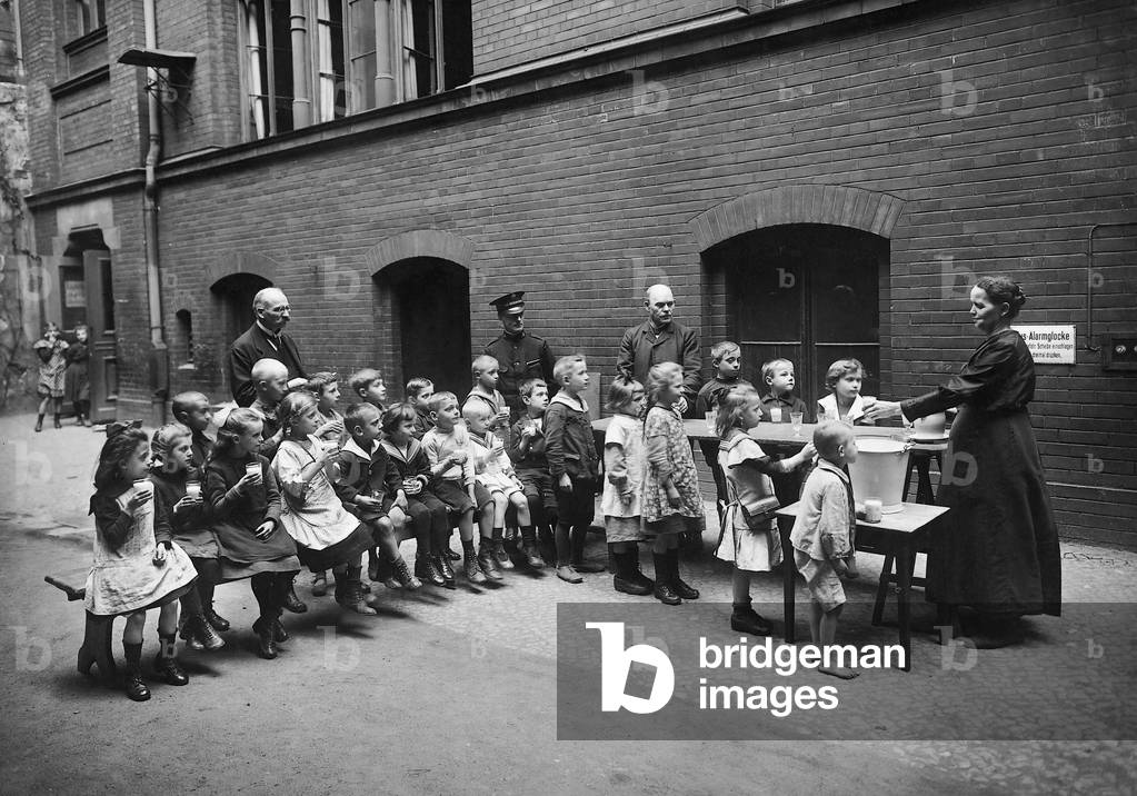 Members of the Salvation Army distribute milk to children in a Berlin elementary school, 1920 (b/w photo)