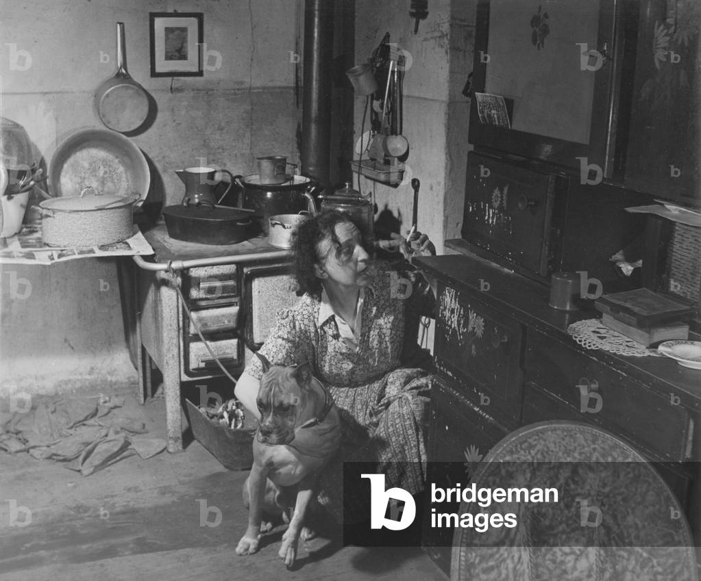 Woman with dog in the kitchen, 1960s (b/w photo)