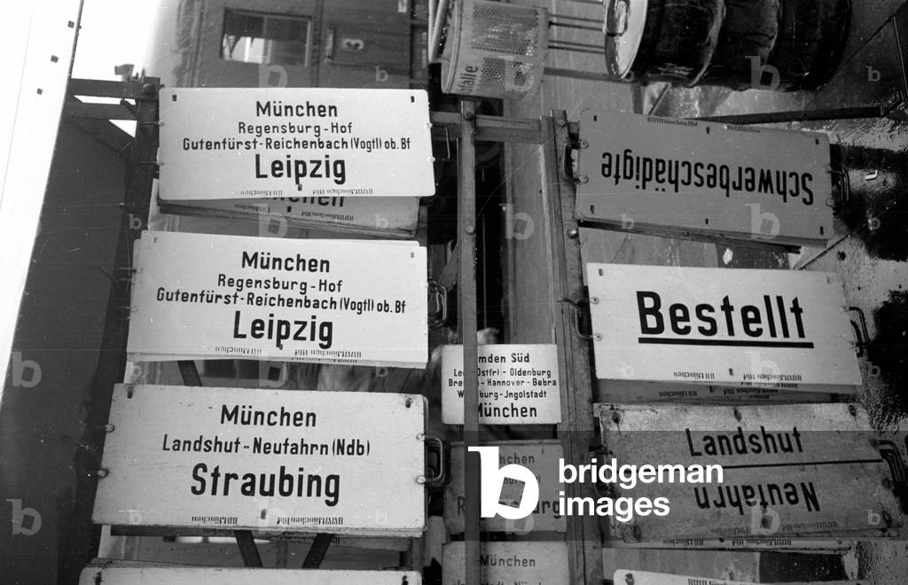Signs for passenger trains on the platform of a train station, 1954 (b/w photo)