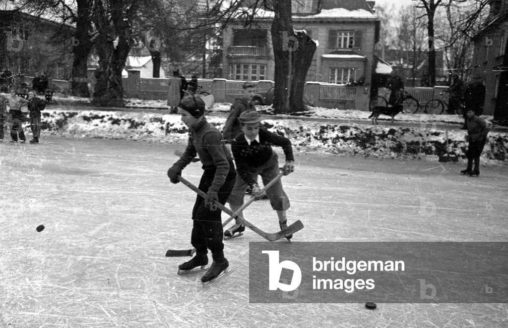 Children playing ice hockey on the frozen Nymphenburg Canal, 1956 (b/w photo)