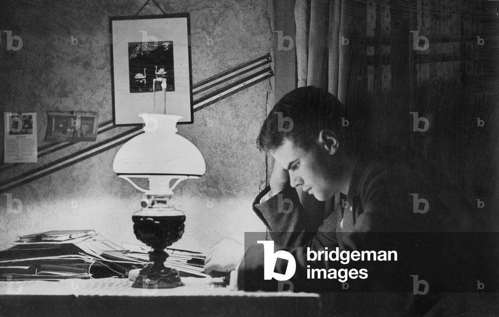 A student reads in his room, 1930 (b/w photo)