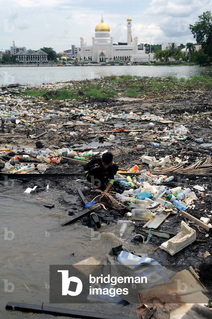 During low tide a man is seen searching for valuables and recycable materials in the muddy rive​r bed of the Brunei River in the capital of the Sultanate of Brunei, Darussalam, Brunei, 2015 (photo)