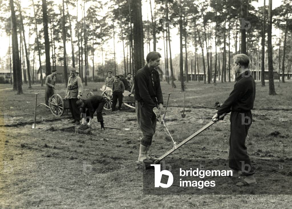 Volunteers restore a sports field, around the 1930s
