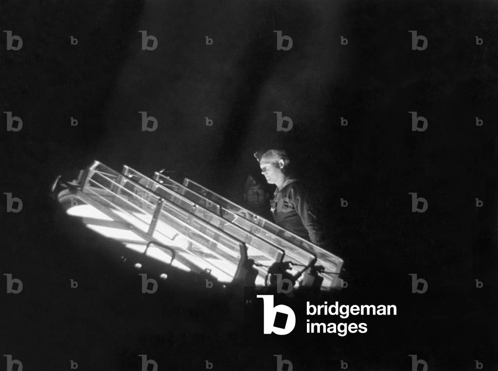 Sailor Checks on the Spotlight of a Battery, 1940 (b/w photo)